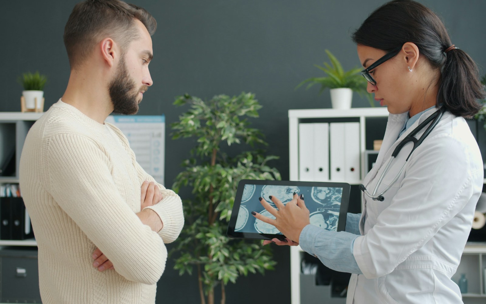 A man reviewing health scans on a tablet with a clinician.